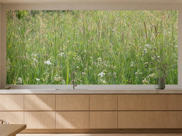 Küchenrückwand „Sommergras zwischen kleinen Wildblüten“ als installierte Rückwand in einer warmen Küche