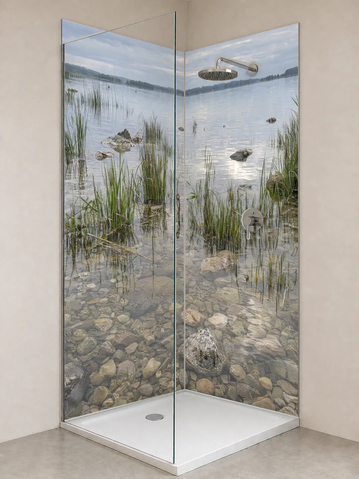 Duschrückwand „Schilf und helle Kiesel im Flachwasser“ als installierte Rückwand in einer hellen Dusche