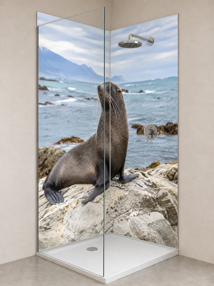 Duschrückwand „Seebär an Kaikouras Felsküste“ als installierte Rückwand in einer hellen Dusche