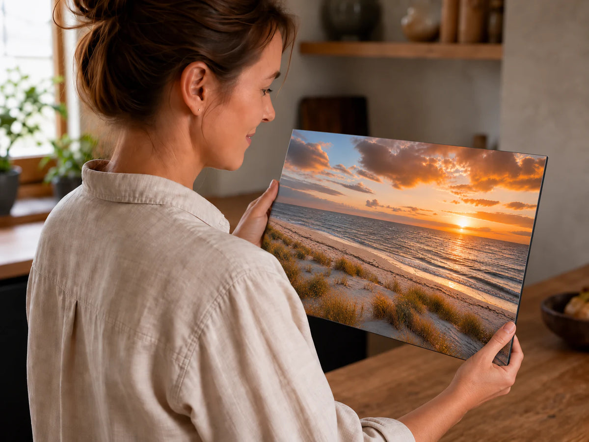 Frau betrachtet eine 60 × 40 cm große Musterplatte im Querformat mit Sonnenuntergangsmotiv in ihrer Küche